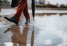 Scarpe bagnate dalla pioggia: come asciugarle senza rovinarle Primo piano di una persona che cammina nella pozzanghera
